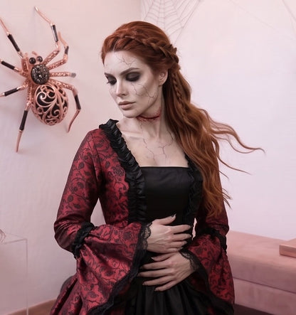 Vestido de época victoriana y corte medieval para mujer en tejido de damasco satinado con estampado floral barroco y panel frontal liso en contraste; presenta escote cuadrado ribeteado con encaje fruncido, mangas largas acampanadas estilo campana, corpiño ajustable tipo corsé en la espalda con lazada y gargantilla a juego. Disponible en cinco variantes de color combinadas con negro: verde esmeralda, morado berenjena, rojo granate, azul petróleo y blanco plateado.