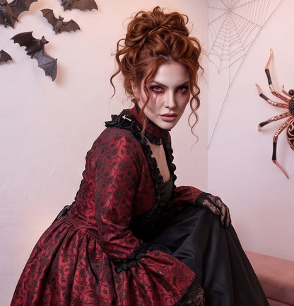 Vestido de época victoriana y corte medieval para mujer en tejido de damasco satinado con estampado floral barroco y panel frontal liso en contraste; presenta escote cuadrado ribeteado con encaje fruncido, mangas largas acampanadas estilo campana, corpiño ajustable tipo corsé en la espalda con lazada y gargantilla a juego. Disponible en cinco variantes de color combinadas con negro: verde esmeralda, morado berenjena, rojo granate, azul petróleo y blanco plateado.