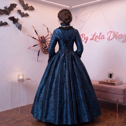 Vestido de época victoriana y corte medieval para mujer en tejido de damasco satinado con estampado floral barroco y panel frontal liso en contraste; presenta escote cuadrado ribeteado con encaje fruncido, mangas largas acampanadas estilo campana, corpiño ajustable tipo corsé en la espalda con lazada y gargantilla a juego. Disponible en cinco variantes de color combinadas con negro: verde esmeralda, morado berenjena, rojo granate, azul petróleo y blanco plateado.